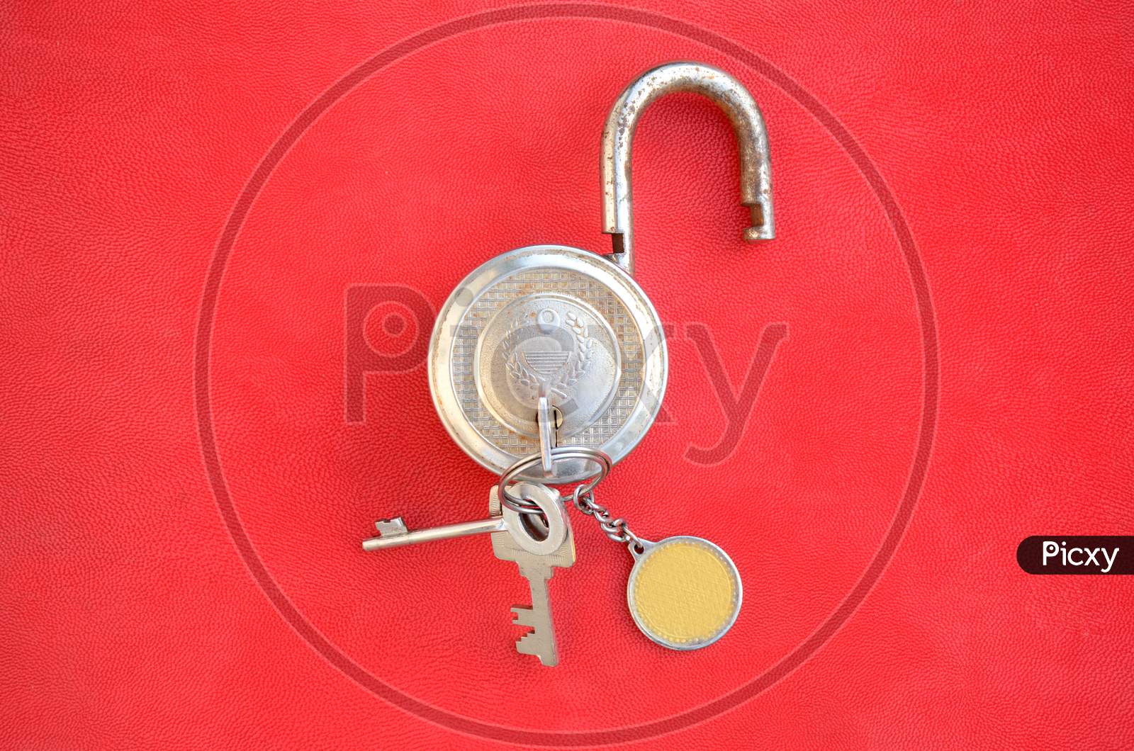 Closeup The Old Brass Metal Door Lock With Key And Key Ring Over Out Of Focus Red Background.