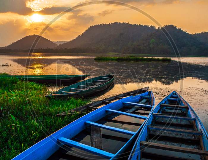Sunset at Chandubi lake with the colourful boats, anchored to the bank.