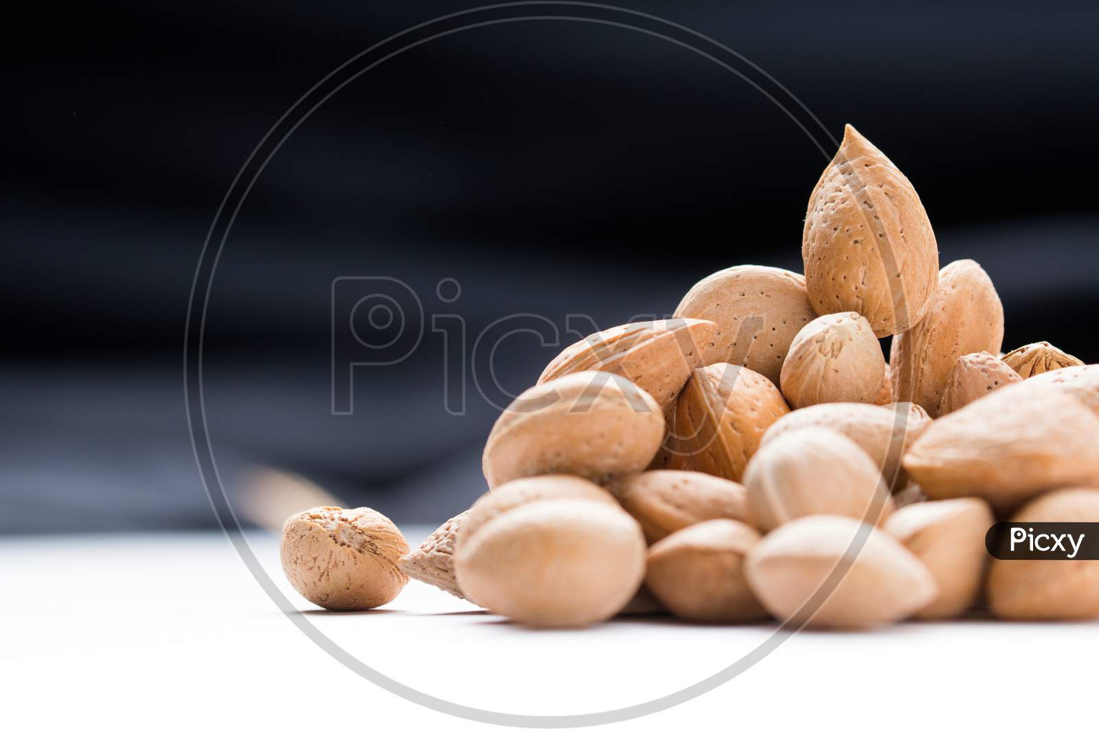 Almonds With Shell, Prunus Amygdalus Heaped On Black Background