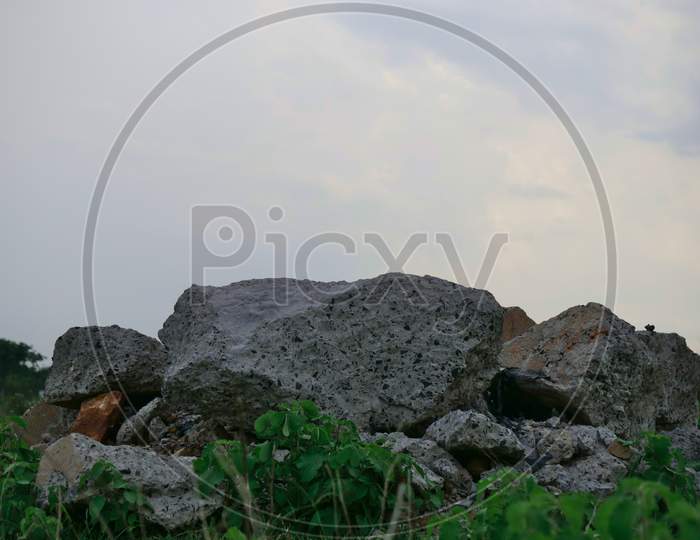 Concrete Waste Material Kept At Grass Field At Sky On Background.