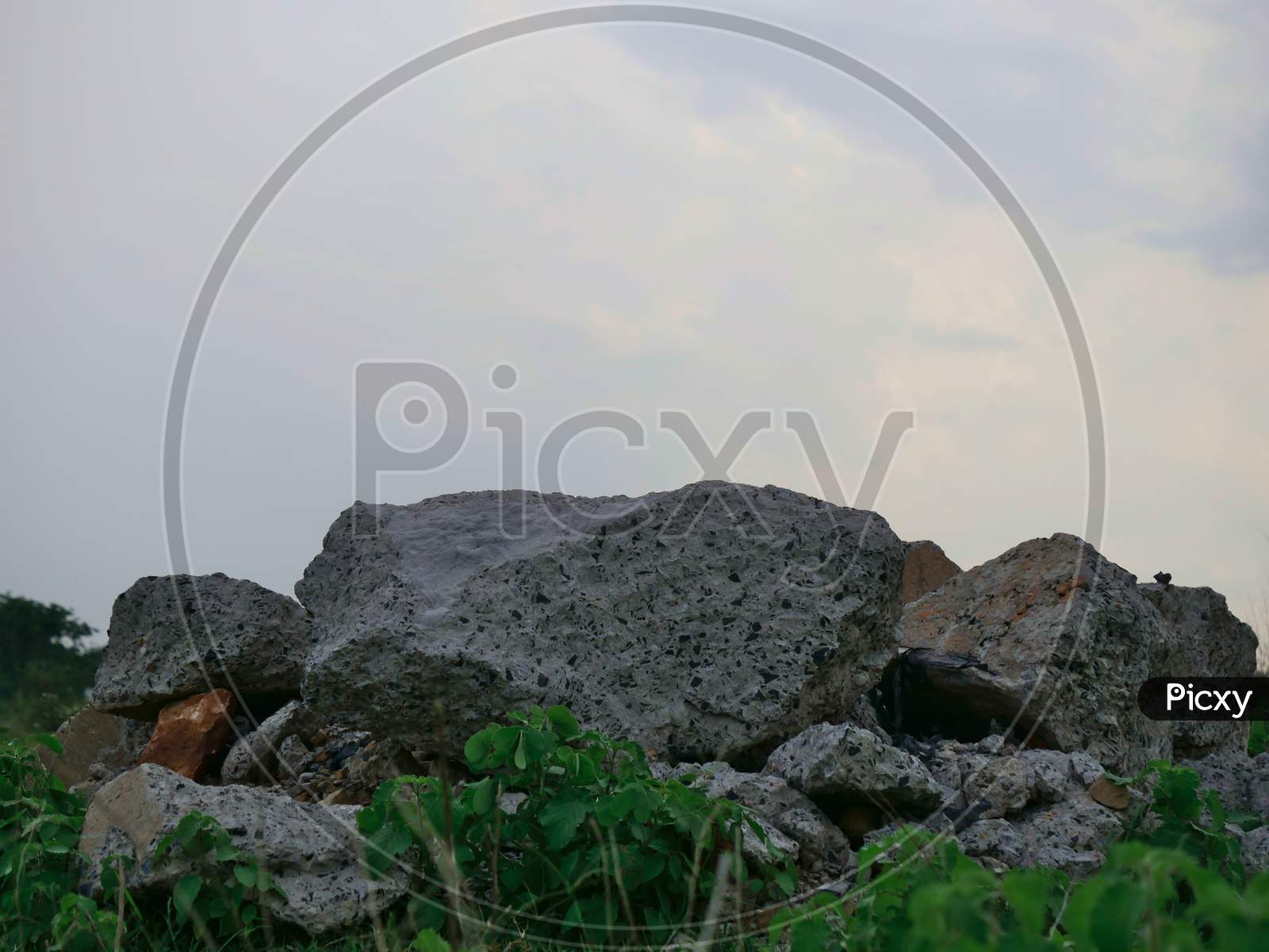 Concrete Waste Material Kept At Grass Field At Sky On Background.