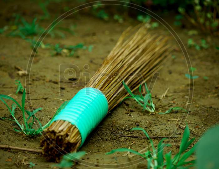 Wooden Stick Broom Isolated On Soil Grass Field, Natural Cleaning Concept.