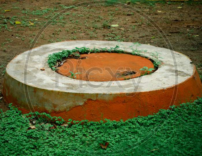 Circle Shape Waste Tank Closed At Natural Green Field In The Garden.