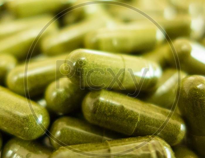Green powdered herbal substance in a soft gel capsule