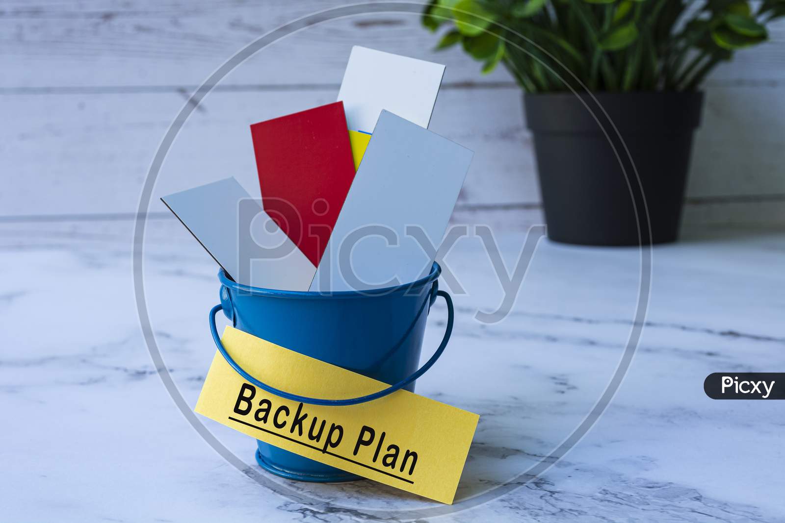 Text On Yellow Paper With Colorful Paper Inside Of A Blue Bucket. Backup Plan