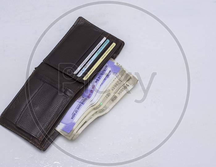 A Wallet With Money And Credit Cards On A White Surface.