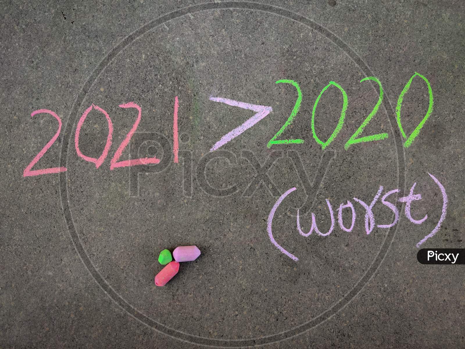 The Inscription Text On The Grey Board, 2021 Greater Than Symbol 2020 (2021 Worst Than 2020) . Using Color Chalk Pieces.