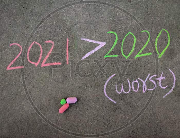The Inscription Text On The Grey Board, 2021 Greater Than Symbol 2020 (2021 Worst Than 2020) . Using Color Chalk Pieces.