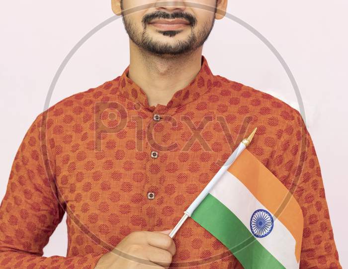 Handsome Indian Boy Or Man In  Ethnic Wear Holding Indian National Flag And Showing Patriotism, Standing Isolated  Background.