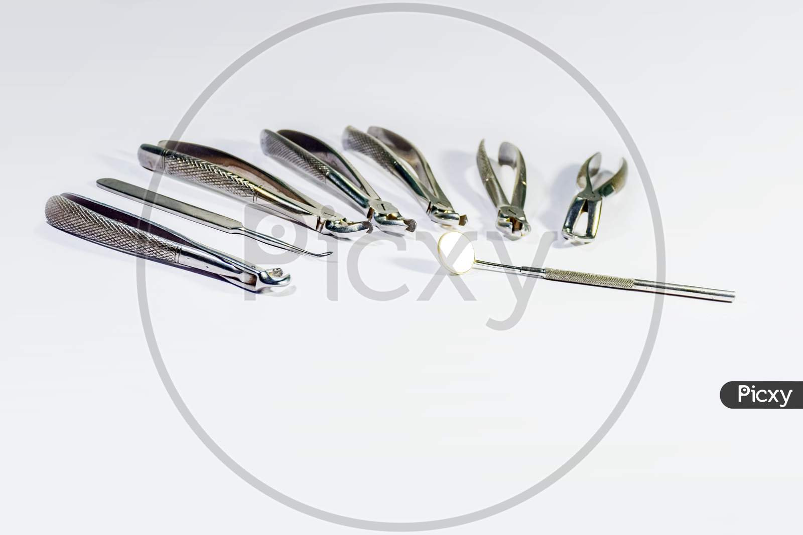 Dental Instruments Arranged On White Table.
