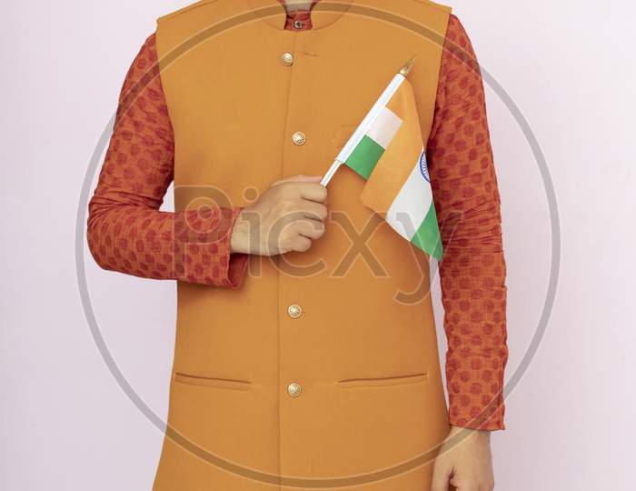 Indian Boy Or Man In Ethnic And Traditional Jacket Wear Holding Indian National Flag And Showing Patriotism, Standing Isolated Background.