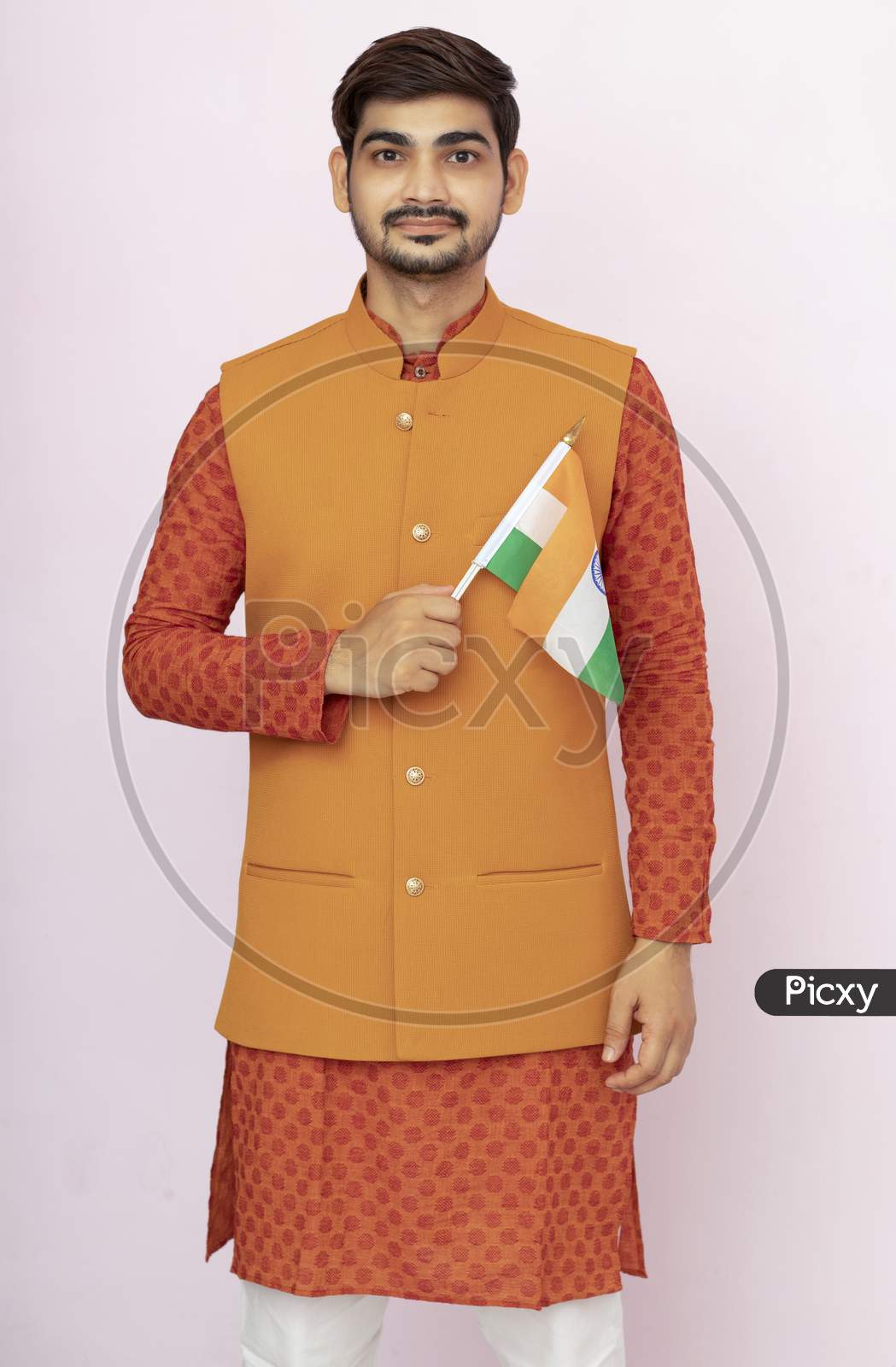 Indian Boy Or Man In Ethnic And Traditional Jacket Wear Holding Indian National Flag And Showing Patriotism, Standing Isolated Background.