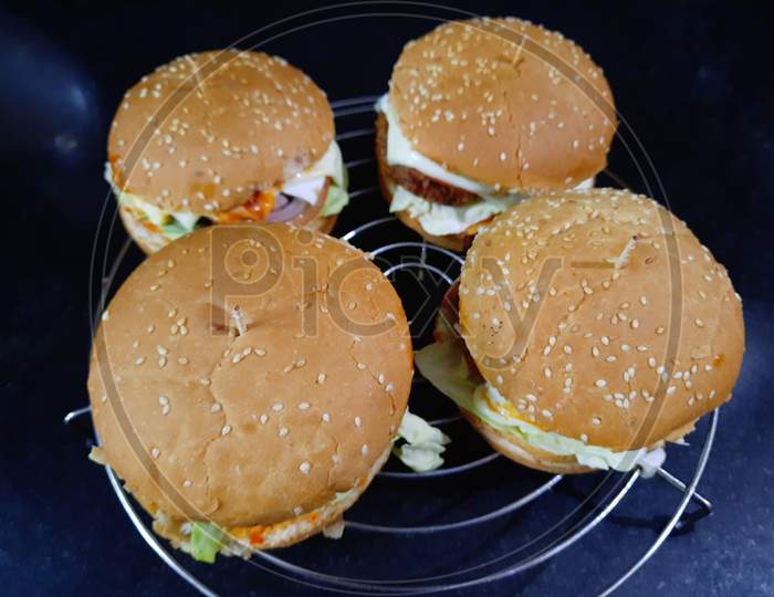 A picture of a freshly prepared and delicious burger, with the filling of cheese, vegetables among other things.