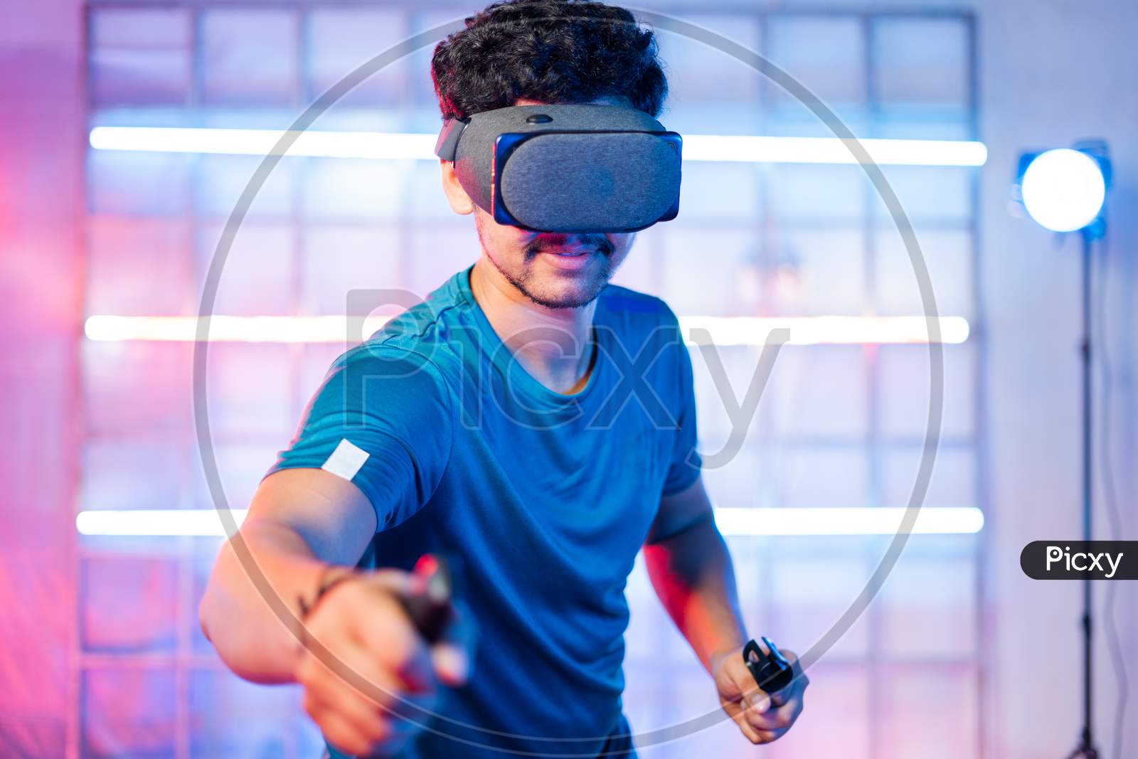 Young Man Playing Video Game By Wearing Vr Or Virtual Reality Goggles And Holding Joysticks In Hands - Concept Of Modern Gaming Technology