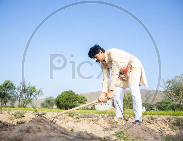 Indian Farmer Digging Farmland, Man Labor Working In Agriculture Field With Farming Tool. Hardworking Male, Clear Blue Sky, Copy Space, Low Angle,