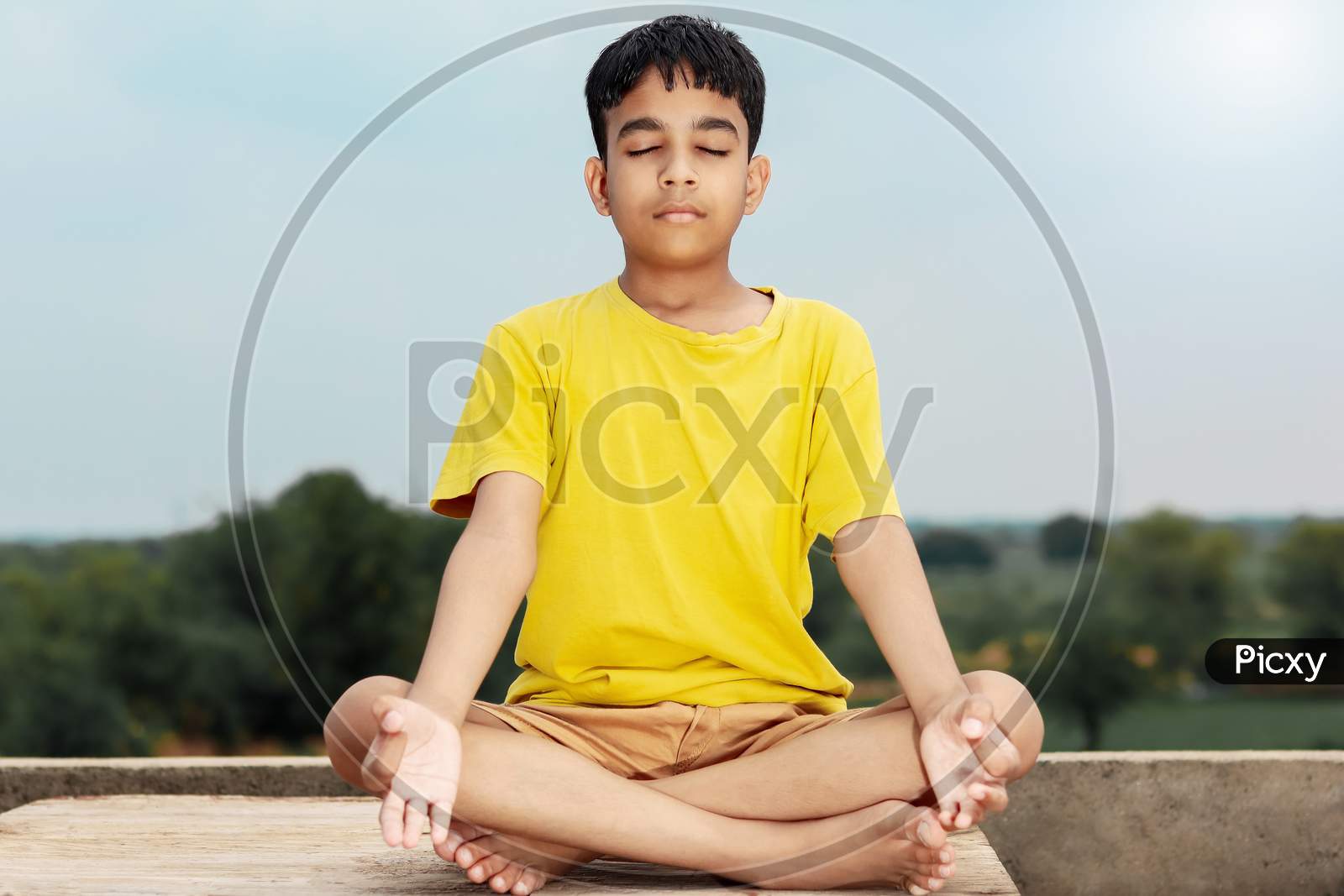A Young Indian Cute Kid Doing Yoga In Mediation Pose