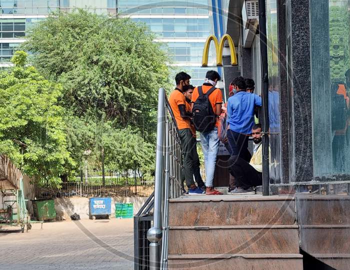 Delivery Boys Riders From Companies Like Swiggy Shadowfax Zomato Standing At A Mcdonalds Takeaway For Online Food Delivery By E-Commerce App Unicorns