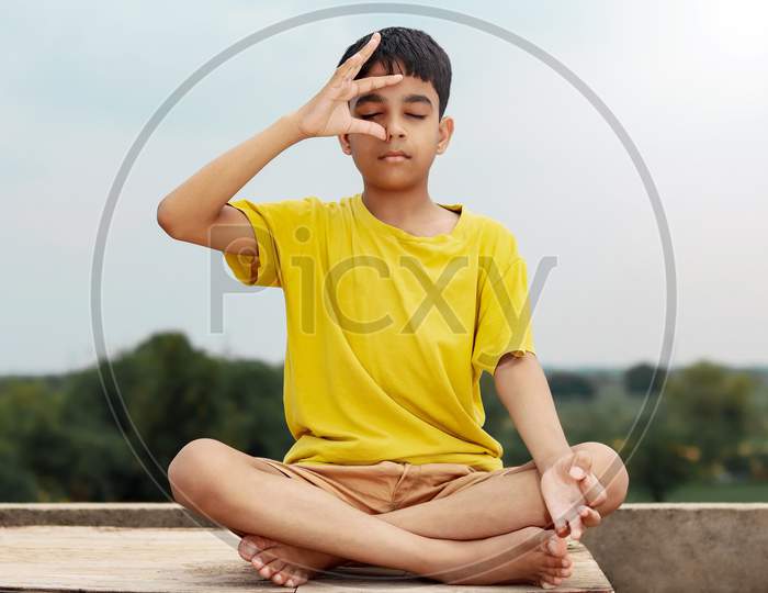 A Young Indian Cute Kid Doing Yoga Anulom Vilom Pose.