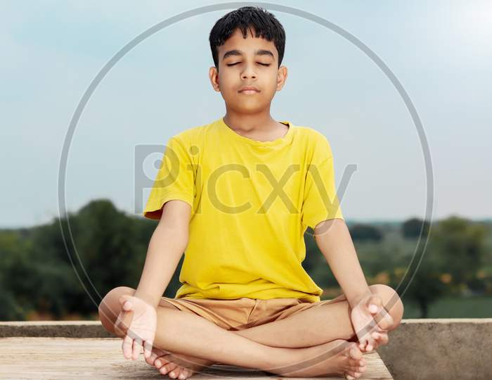 A Young Indian Cute Kid Doing Yoga In Mediation Pose