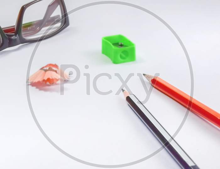 Back To School Concept- A Pencil,Erasor, Sharpner An Cut Foil Of The Pencil On White Table With Or Without Spectacles Not Properly Aranged Isolated.