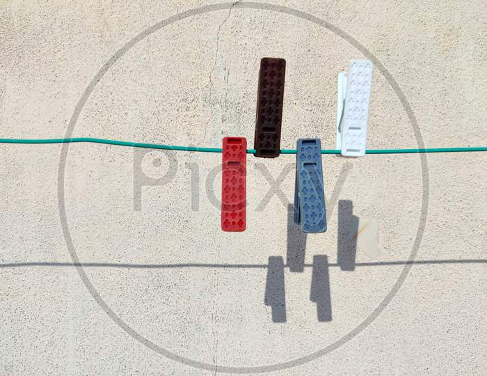 Four Colorful Cloth Clip Or Plastic Clothespins On The Rope With Shadows On White Background
