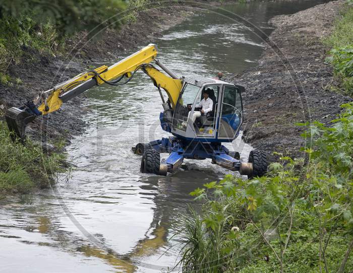 Excavator Performing River Dredging And Clearing Up The River Banks