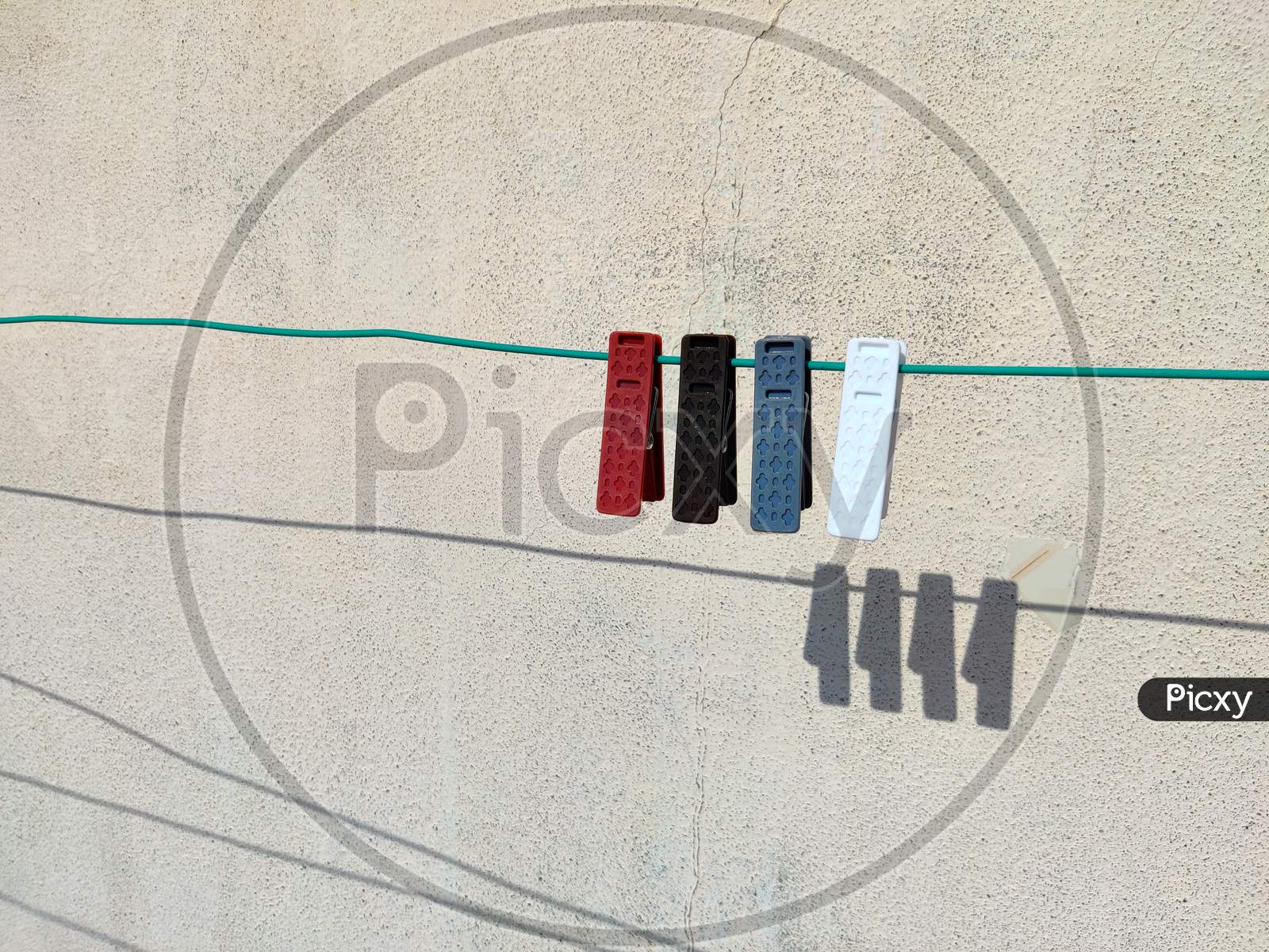 Side View Of Grey,Red,Brown And White Color Clothespins Or Cloth Clips On The Rope With Shadows In Back. White Background