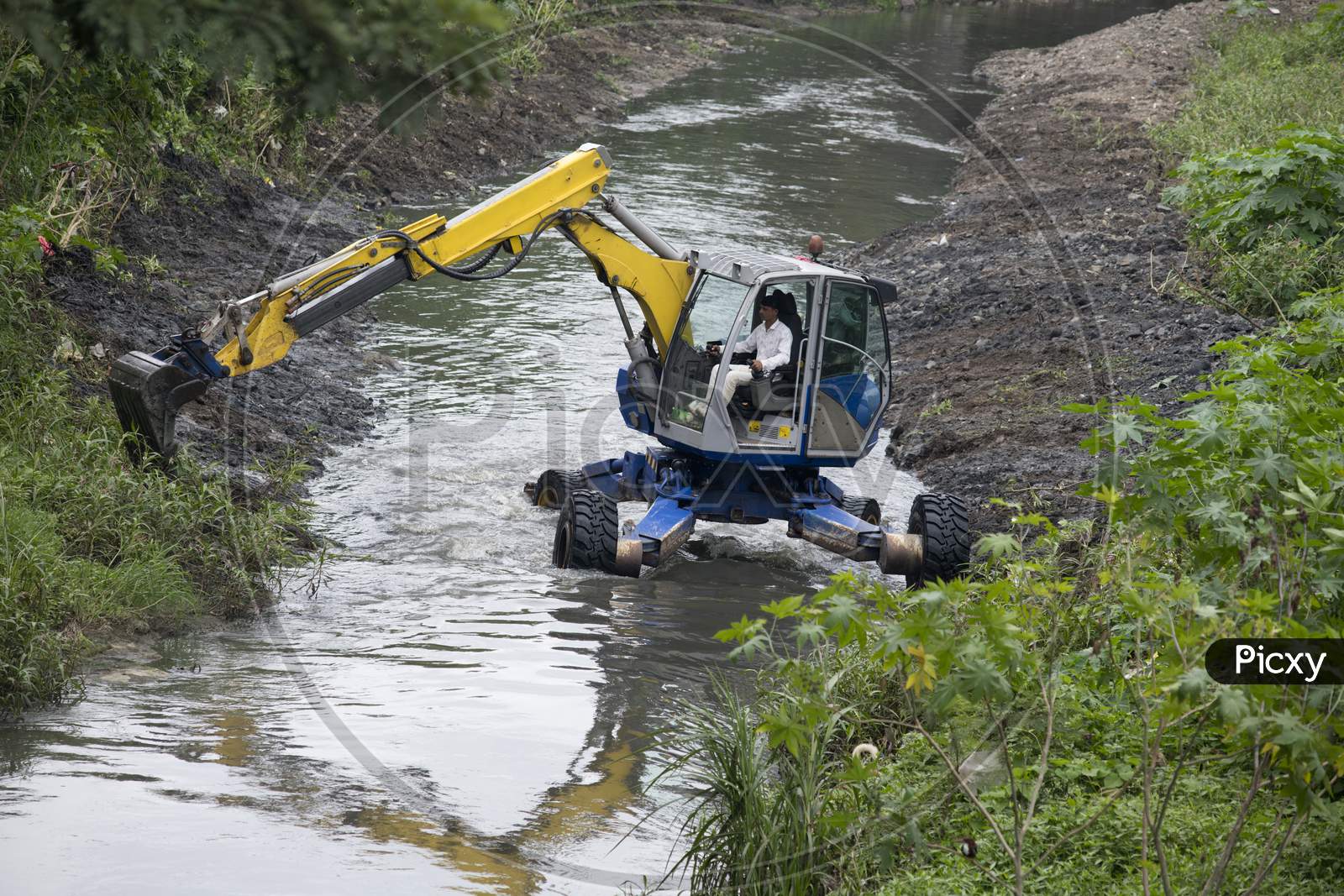 Excavator Performing River Dredging And Clearing Up The River Banks