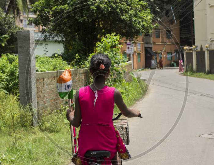 15Th August, 2021, Kolkata, West Bengal, India: A Young Girl Cycling And A Indian Flag Shaped Balloon In Her Hand.