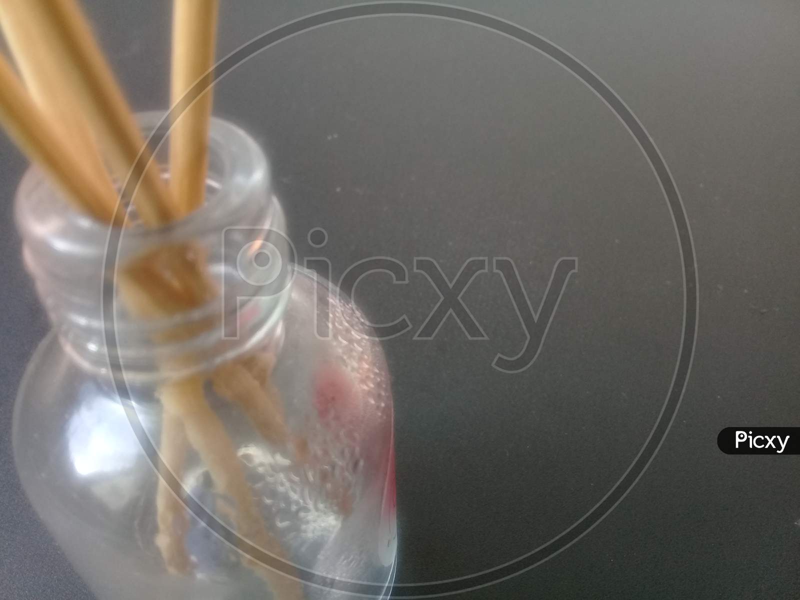 Close-Up Of Incense Sticks In Glass Container Against Gray Background