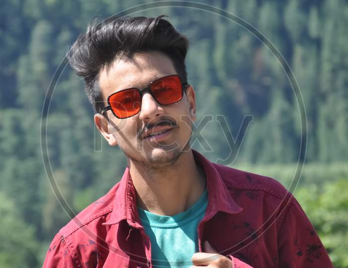 Closeup shot of a North Indian young guy posing outdoor with wearing red shirt and red sunglasses with looking at camera