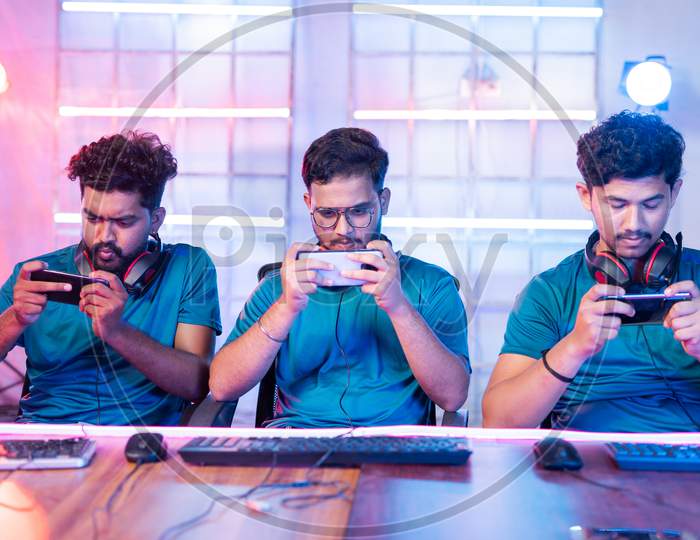 Front View Of Team Of Young Professional Gamers Seriously Playing Of Live Video Game On Mobile Phone At Esports Tournament.