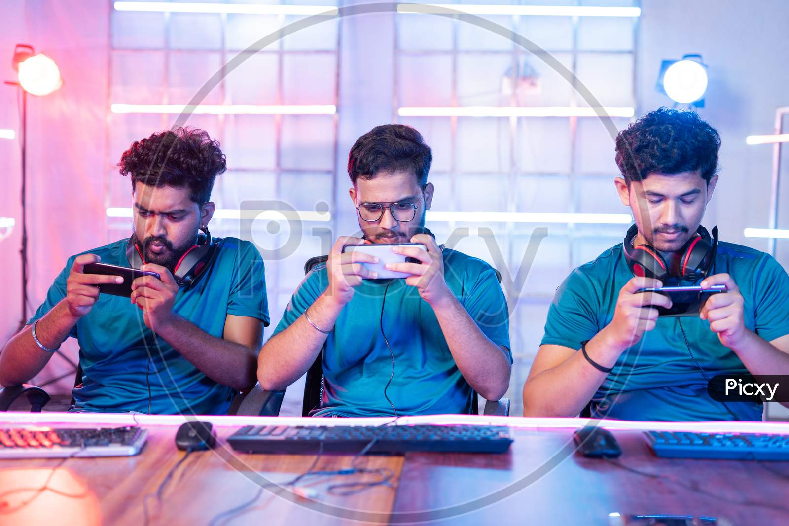 Front View Of Team Of Young Professional Gamers Seriously Playing Of Live Video Game On Mobile Phone At Esports Tournament.
