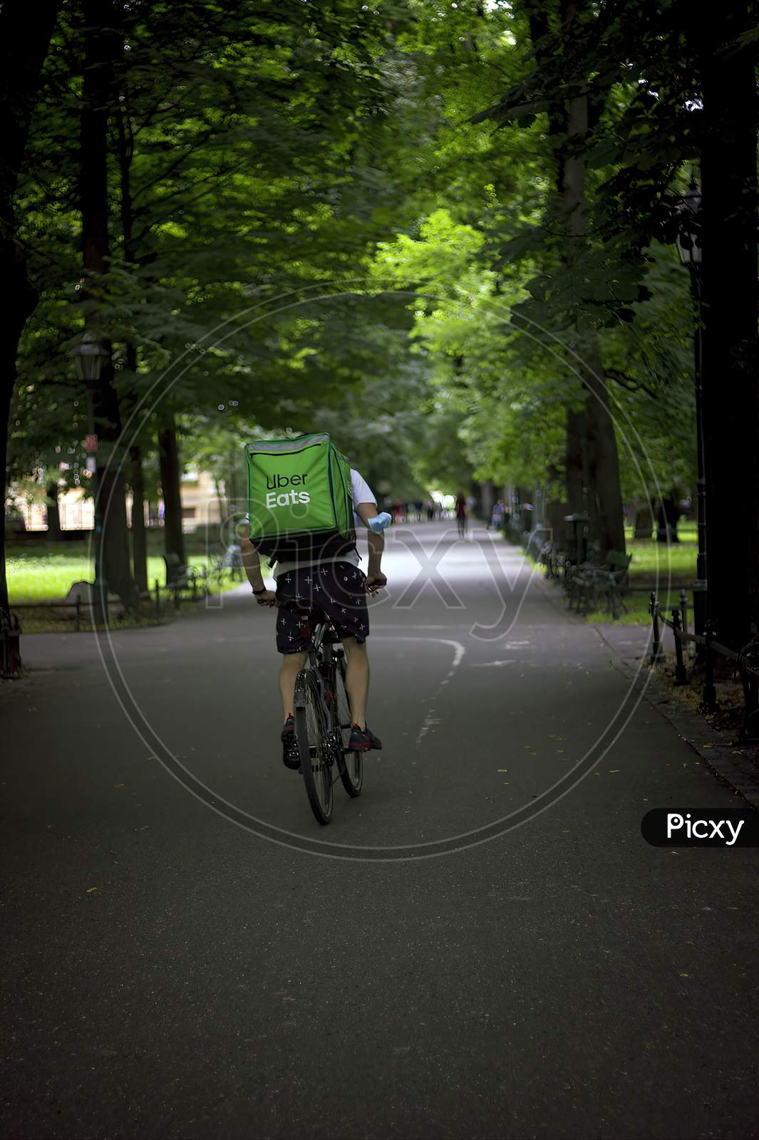 Krakow, Poland - August 01, 2021: A Delivery Man In A Bicycle Riding Through A Street In Order To Delivering Food In A Huge Bag Pack