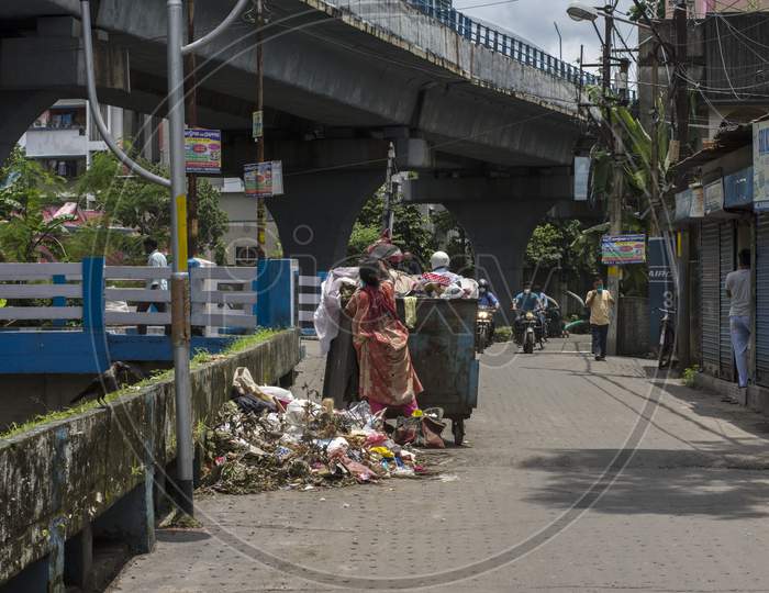 15Th August, 2021, Kolkata, West Bengal, India: A Public Dustbin Full With Garbage And A Lady Collecting Something From That. Concept Of Pollution And Unhealthy Living.