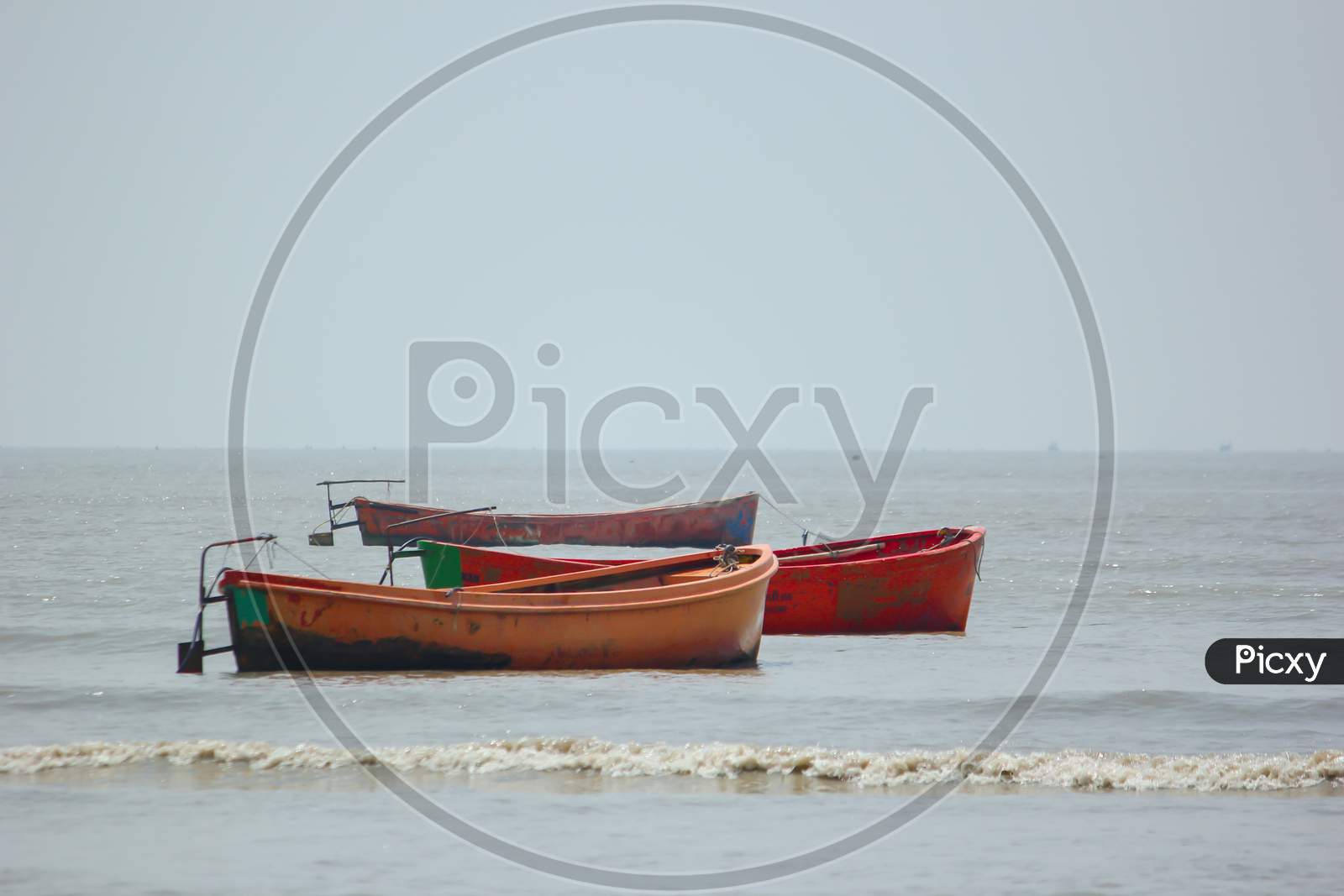 Image of Three multicolored plastic fishing boats anchored