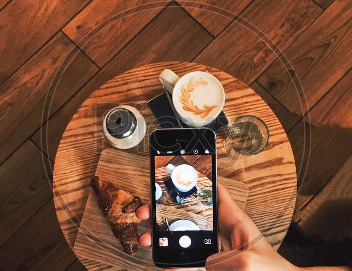 Woman taking photo of coffee on mobile device