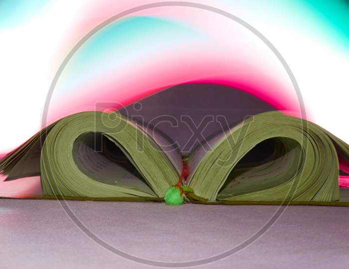 Holy Book Presented On Pink Rays Light Effect Background.