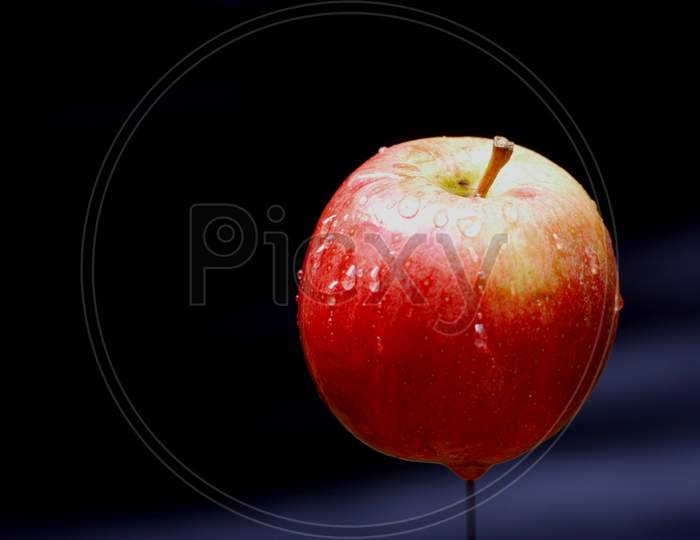 Flying Single Red Color Fresh Apple With Water Drops Isolated On Black Background, Organic Commercial Food Image.