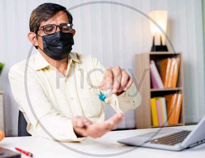 Businessman At Office With Medical Mask Using Hand Sanitizer Before Starting Work - Concept Of Office Reopen, New Normal And Coronavirus Covid-19 Safety Healthcare Measures.
