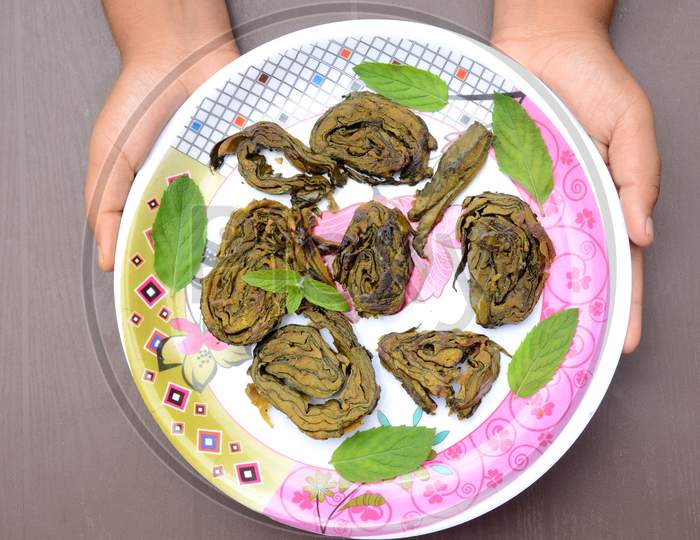 Closeup The Fried Arabic Leaves Food With Green Mint In The Plate Hold Hand Over Out Of Focus Brown Background.