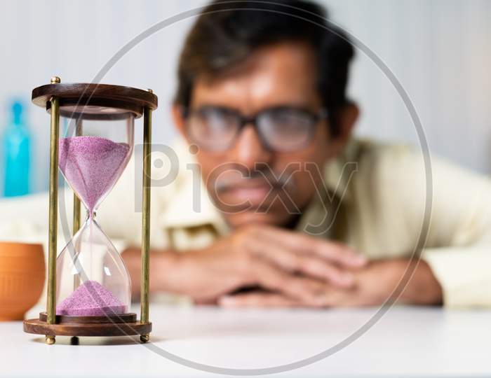 Focus On Hourglass, Businessman At Office Looking Hourglass - Concpet Of Time Management And Waitng For Good Time