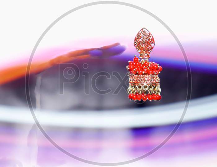 Female Red Color Earrings Presented On Air With Light Effect Shine Backdrop, Commercial Product Presentation Image.