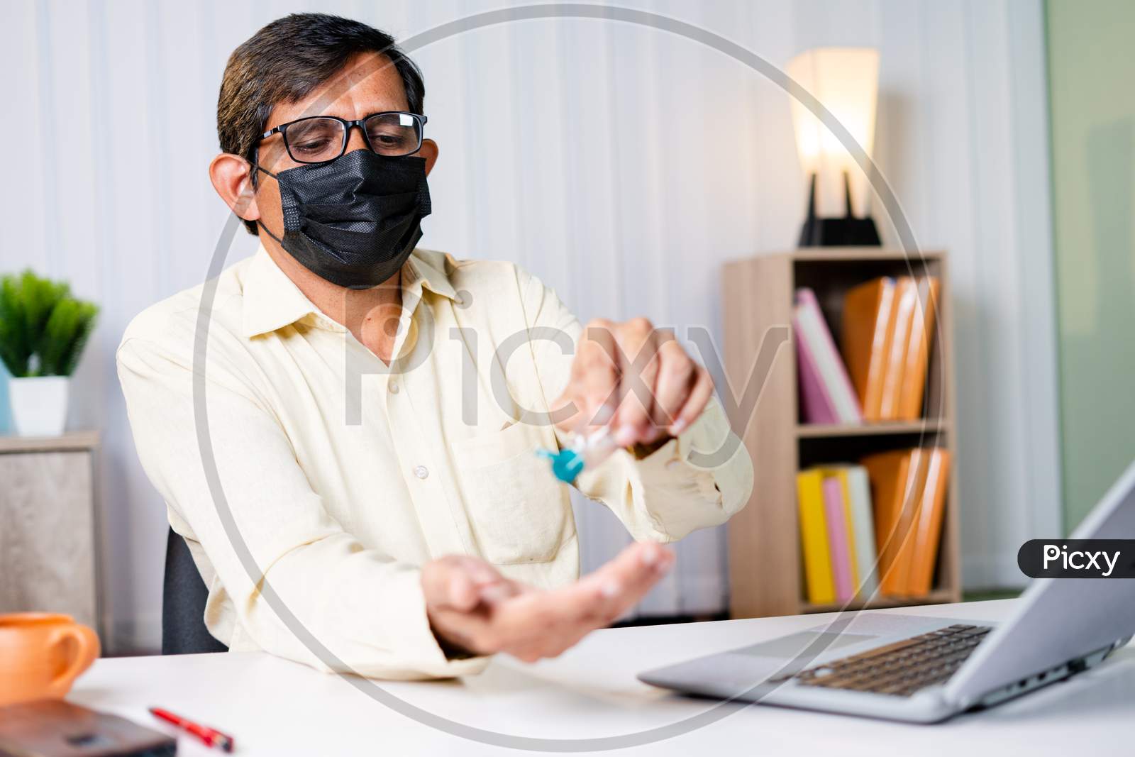 Businessman At Office With Medical Mask Using Hand Sanitizer Before Starting Work - Concept Of Office Reopen, New Normal And Coronavirus Covid-19 Safety Healthcare Measures.