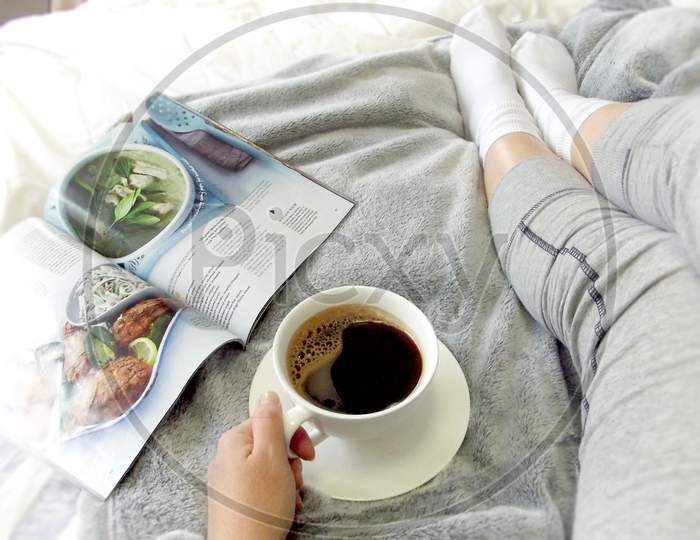 Relaxing in bed with coffee and a magazine