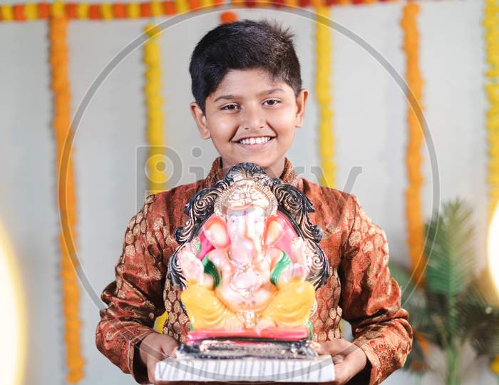 Happy Smiling Kid During Ganesha Festival With Traditional Dress Bringing By Holding Lord Vinaya To Home For Religious Celebration