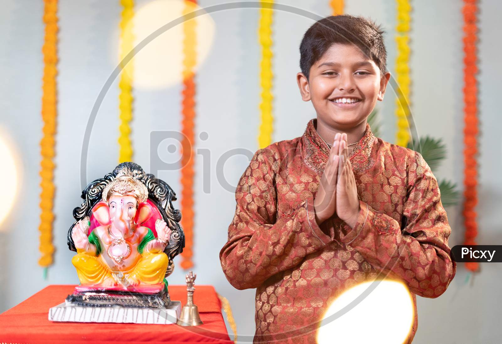 Happy Smiling Kid During Ganesha Festival With Traditional Dress Doing Namaste On Decorated Background