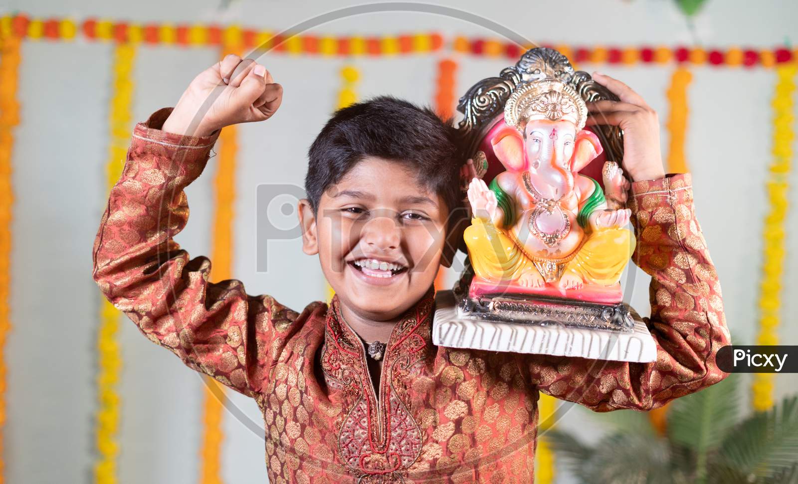 Happy Smiling Kid With Ganesha Idol On Shoulder Saying Or Chanting Ganapati Bappa Morya During Festival Celebrations