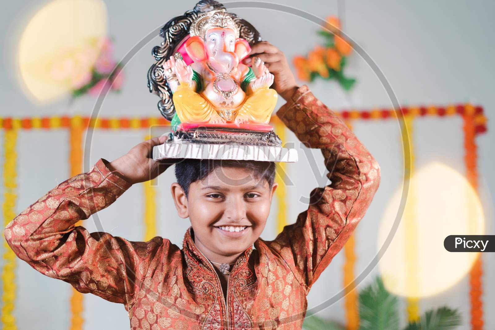 Happy Smiling Kid During Ganesha Festival With Traditional Dress Carrying Lord Vinayaka For Visarjan Or Immersion During Religious Celebration