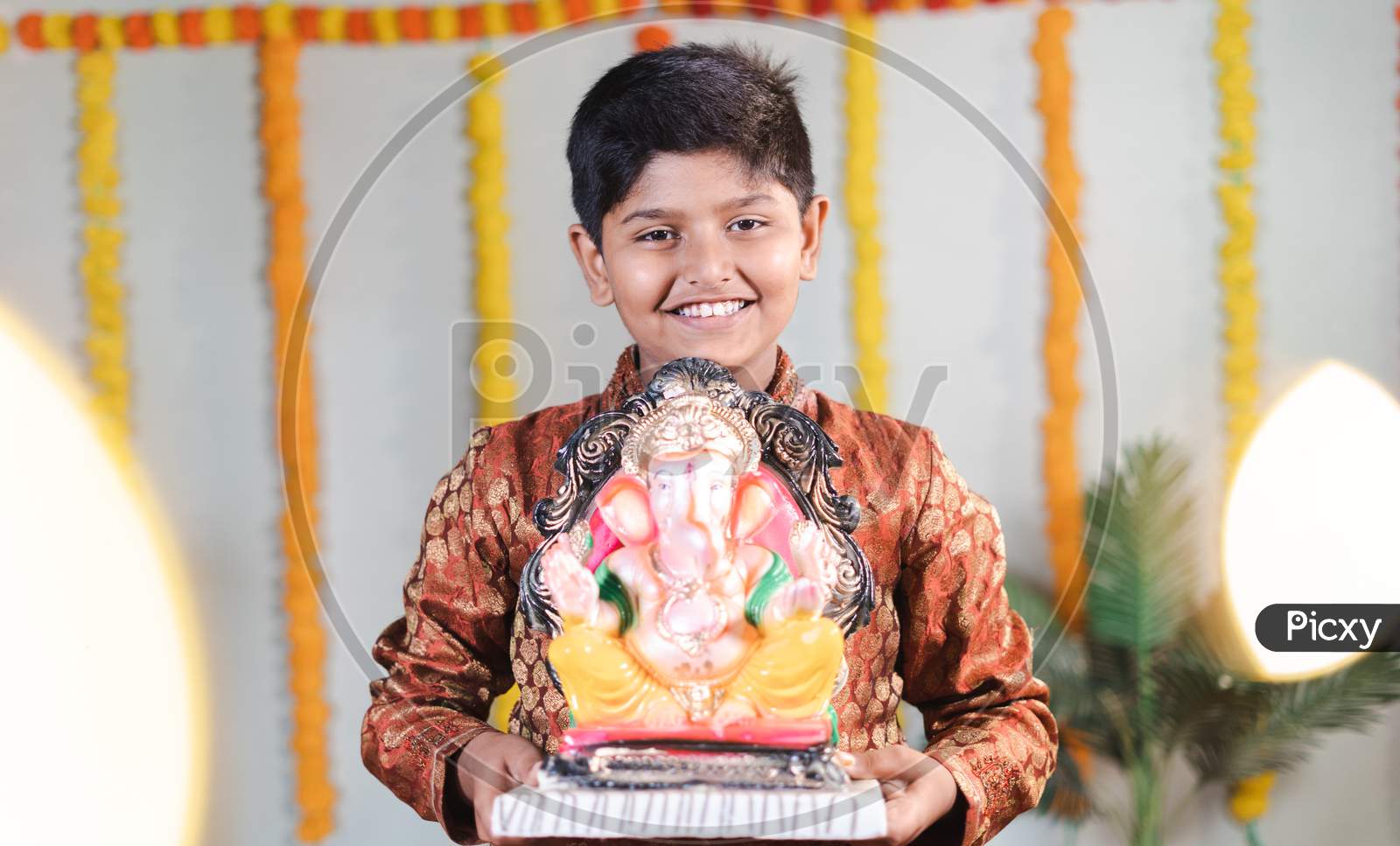 Happy Smiling Kid During Ganesha Festival With Traditional Dress Bringing By Holding Lord Vinaya To Home For Religious Celebration